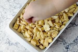 colocando trozos de mantequilla encima de las manzanas en el molde