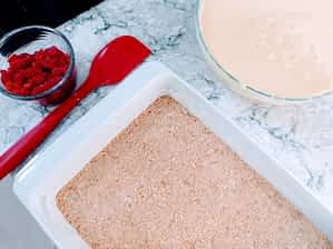 la base, el relleno, y las frambuesas listos para montar las barritas