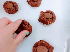 poniendo bolitas de Nutella congelada adentro de las bolas de masa de galletas