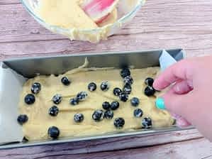 esparciendo arándanos encima de la masa de bizcocho en el molde