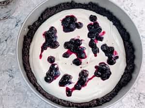 preparación del cheesecake sin horno poniendo la capa de frutas encima de la primera capa de relleno Philadelphia