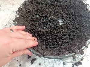 presionando la masa de corteza Oreo al lado del molde con la mano