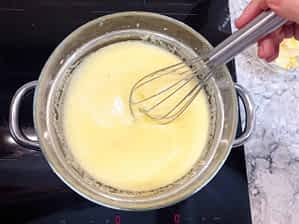 mezclando con una batidora de varillas la salsa de limón en un baño Maria