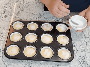 espolvoreando azúcar encima de la masa de magdalenas