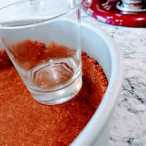 usando un vaso para aplanar la base de galletas