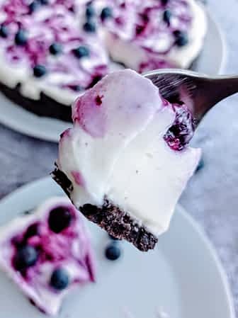 Una cucharada con un bocado de cheesecake sin horno de arándanos