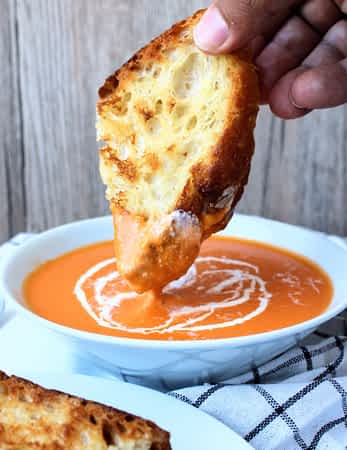 mojando un sándwich de queso fundido en la sopa