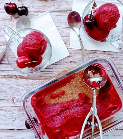 un recipiente y dos tazas con sorbete de cerezas adentro