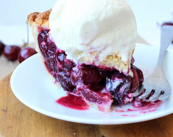 un trozo de pay de cerezas con una bola de helado casero encima