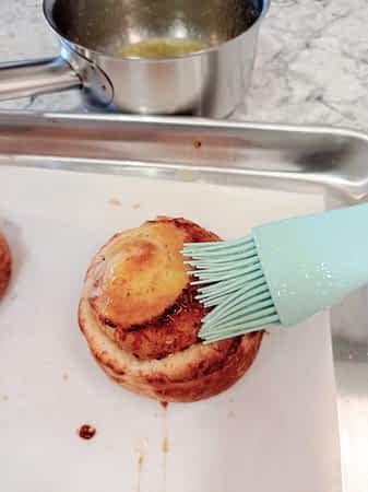 usando un pincel para cubrir un roll de queso con mantequilla derretida