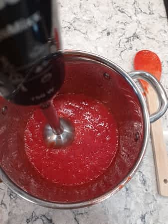 Pasa una licuadora para hacer la salsa más lisa. triturando la salsa de fresas con una licuadora