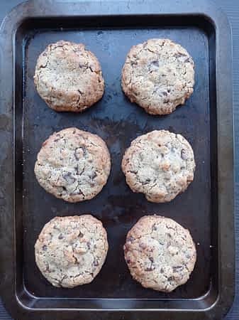 Pon al máximo 6 galletas en una bandeja y hornéalas aprox 10 minutos. seis galletas de chocolate en una bandeja