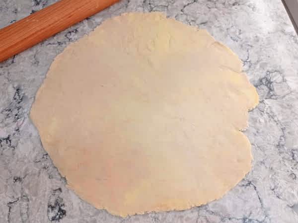 Extiende una masa de pay a un círculo de aprox. 40cm de diámetro. la masa extendida en la encimera