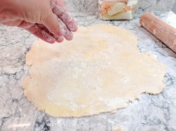 espolvoreando harina encima de la masa de pie en la encimera