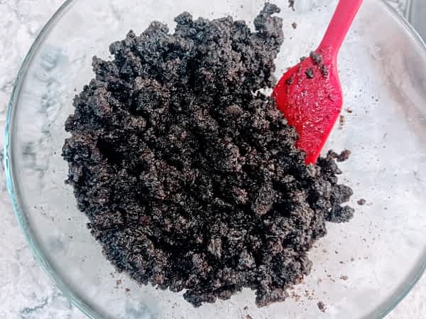 La masa para la base se ve como arena húmeda. la base de galleta en un tazón parece arena húmeda