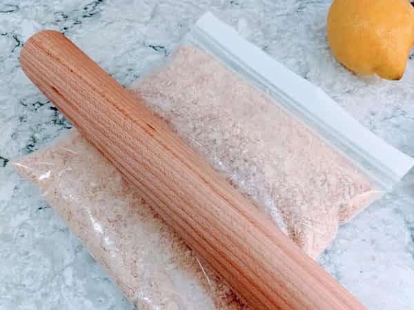 el rodillo de cocina aplastando las galletas de la base en una bolsa