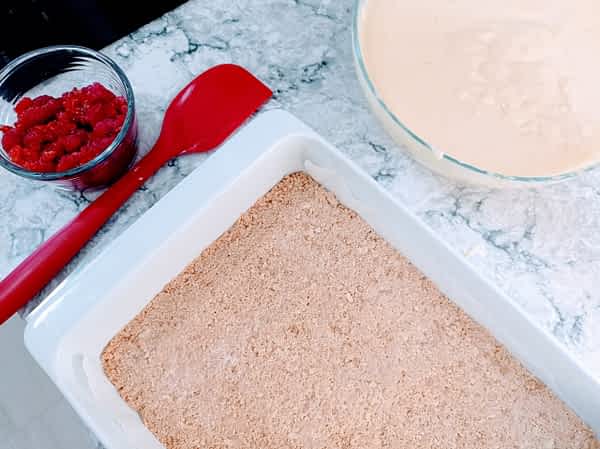 la base, el relleno, y las frambuesas listos para montar las barritas