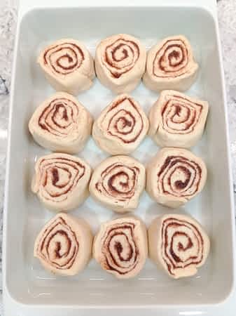 los cinnamon rolls cortados y organizados en el molde, 3 por 4