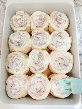pintando con nata los cinnamon rolls en un molde