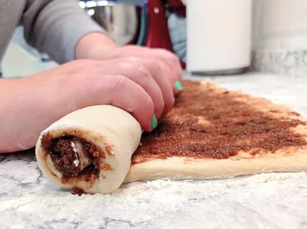 enrollando el rectángulo de masa rellenado de azúcar y canela