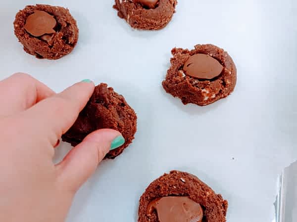 poniendo bolitas de Nutella congelada adentro de las bolas de masa de galletas