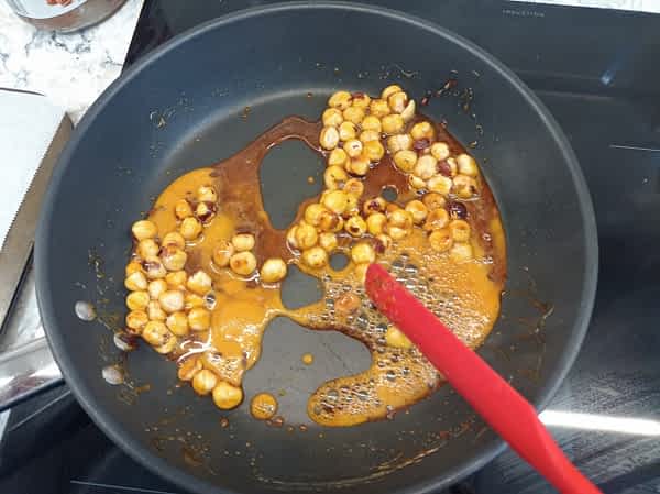 mezclando las avellanas en el sartén con el azúcar derretido