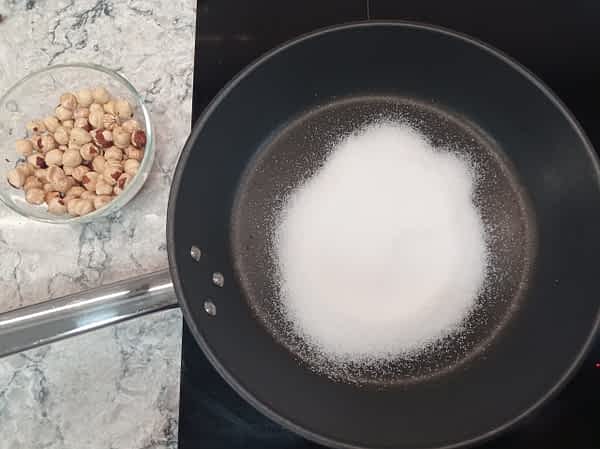azúcar en un sartén para derretir y hacer avellanas caramelizadas