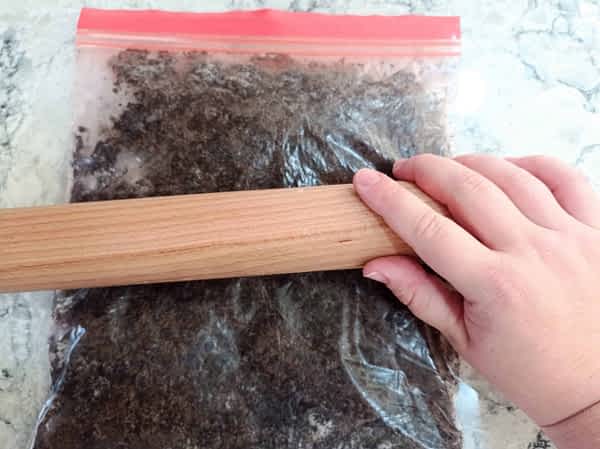 aplastando las galletas Oreo en una bolsa con un rodillo de cocina