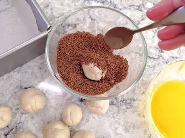 bolita de masa en la mezcla de canela y azúcar