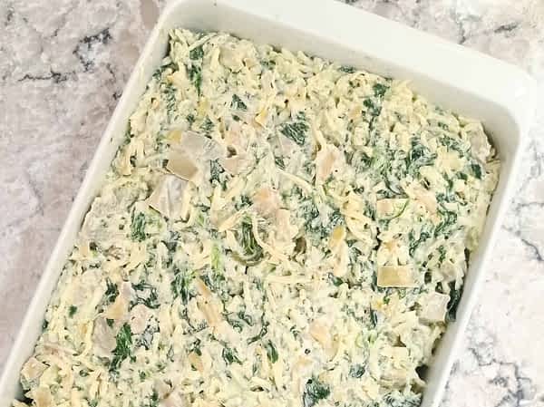 dip de espinacas y alcachofas en una cacerola listo para el horno