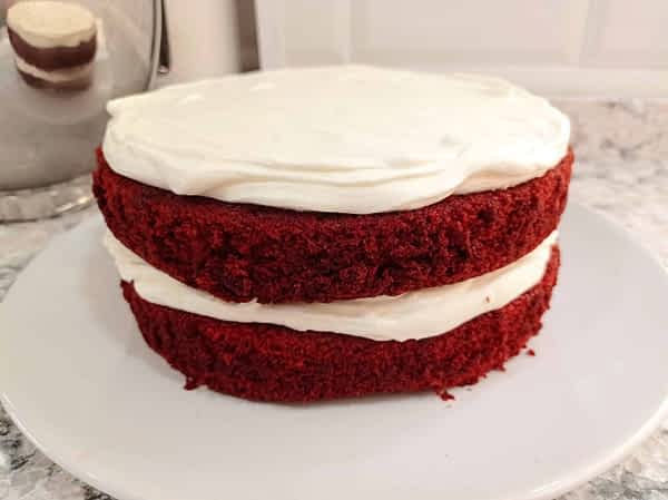 Poner el segundo bizcocho encima y untar con más glaseado. Opcionalmente, untar los lados también. las dos capas de tarta red velvet montadas