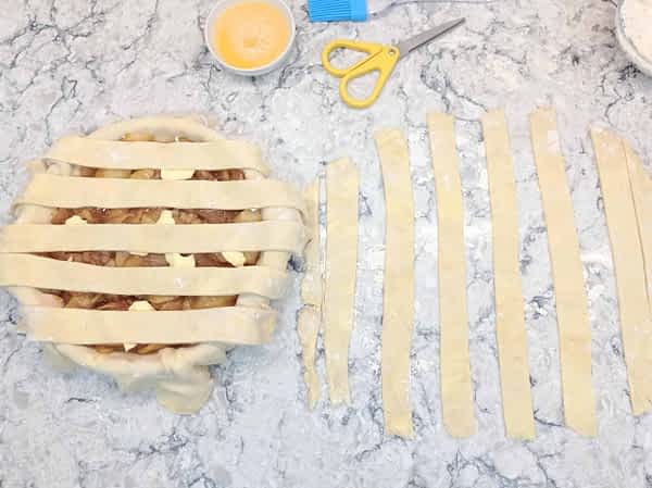 Poner cada otra tira encima del relleno, dejando el espacio deseado entre ellas. poner las tiras horizontales con espacio