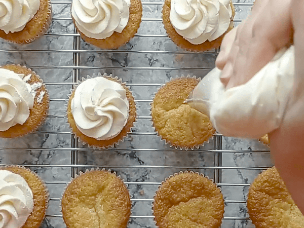 poniendo glaseado encima de los cupcakes