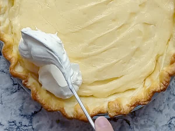 esparciendo nata montada encima de la crema pastelera