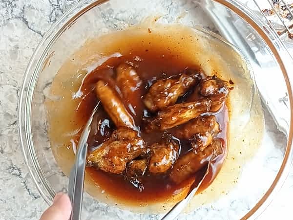 mezclando las alitas con la salsa barbacoa y miel