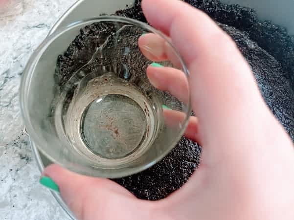 presionando la base de galletas con el fondo de un vaso