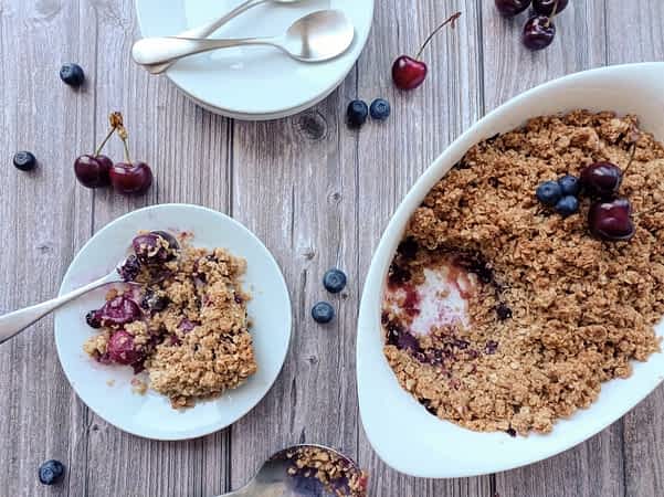 vista desde arriba de la mesa con la cacerola de crisp de cerezas y unos platos al lado
