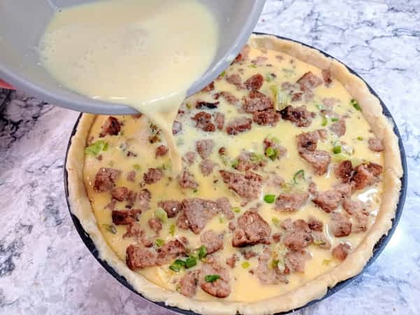 vertiendo la mezcla de huevos en la masa de la quiche