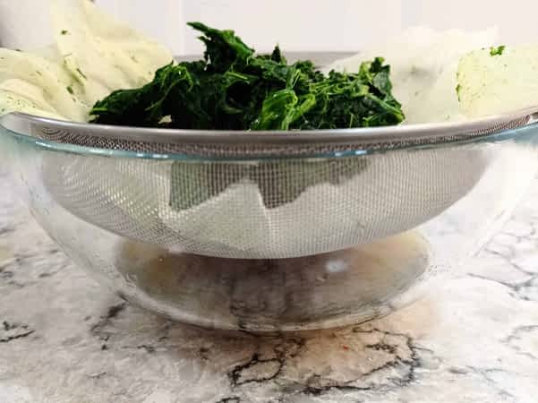 escurriendo las espinacas congeladas en un colador