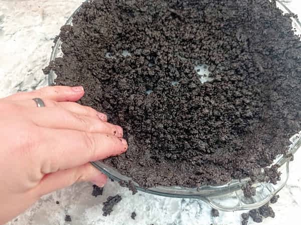 presionando la masa de corteza Oreo al lado del molde con la mano