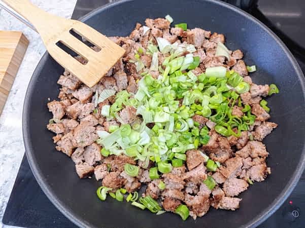 salchicha y cebolla cocinando en una sartén