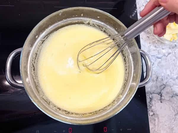 mezclando con una batidora de varillas la salsa de limón en un baño Maria