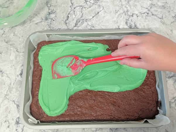 rociar glaseado de menta encima de brownies horneados