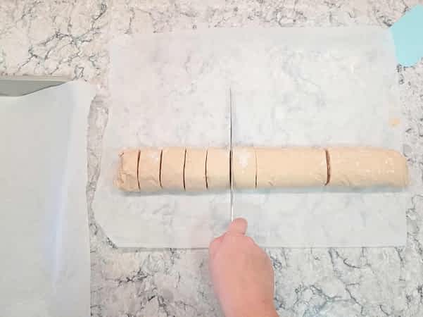 cortando el cilindro de rollos de canela y manzana