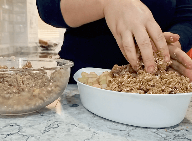 poniendo el topping de avena encima de las manzanas