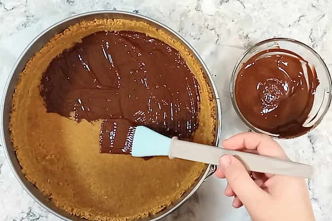 pintando el chocolate derretido encima de la base de galletas