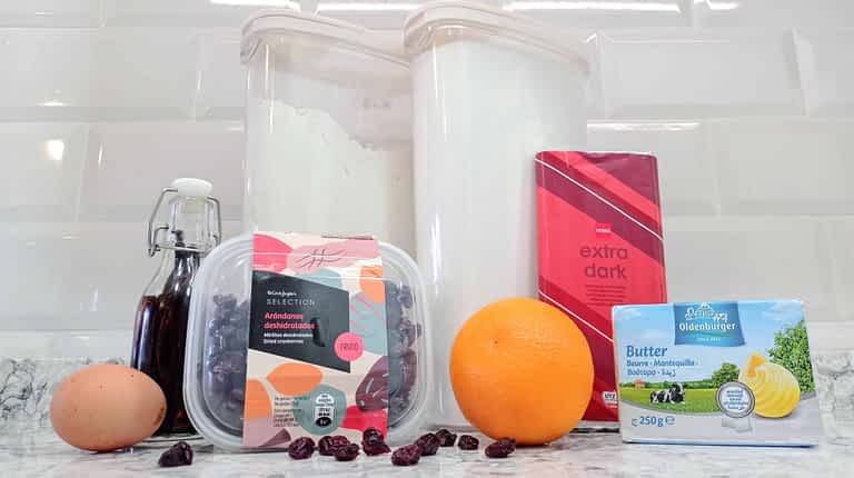 ingredientes para hacer galletas de arándanos rojos, naranja, y chocolate en una bandeja