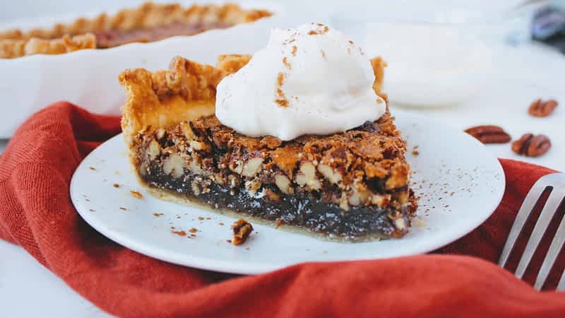 un trozo de pay de pecanas con nata montada