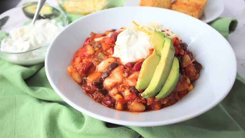 un bol de chili vegetariano con crema agria, aguacate, y queso encima